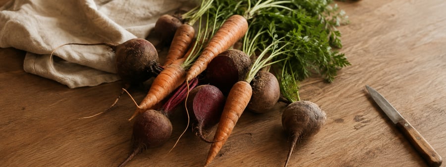 Fresh carrots and beets arranged on a wooden table