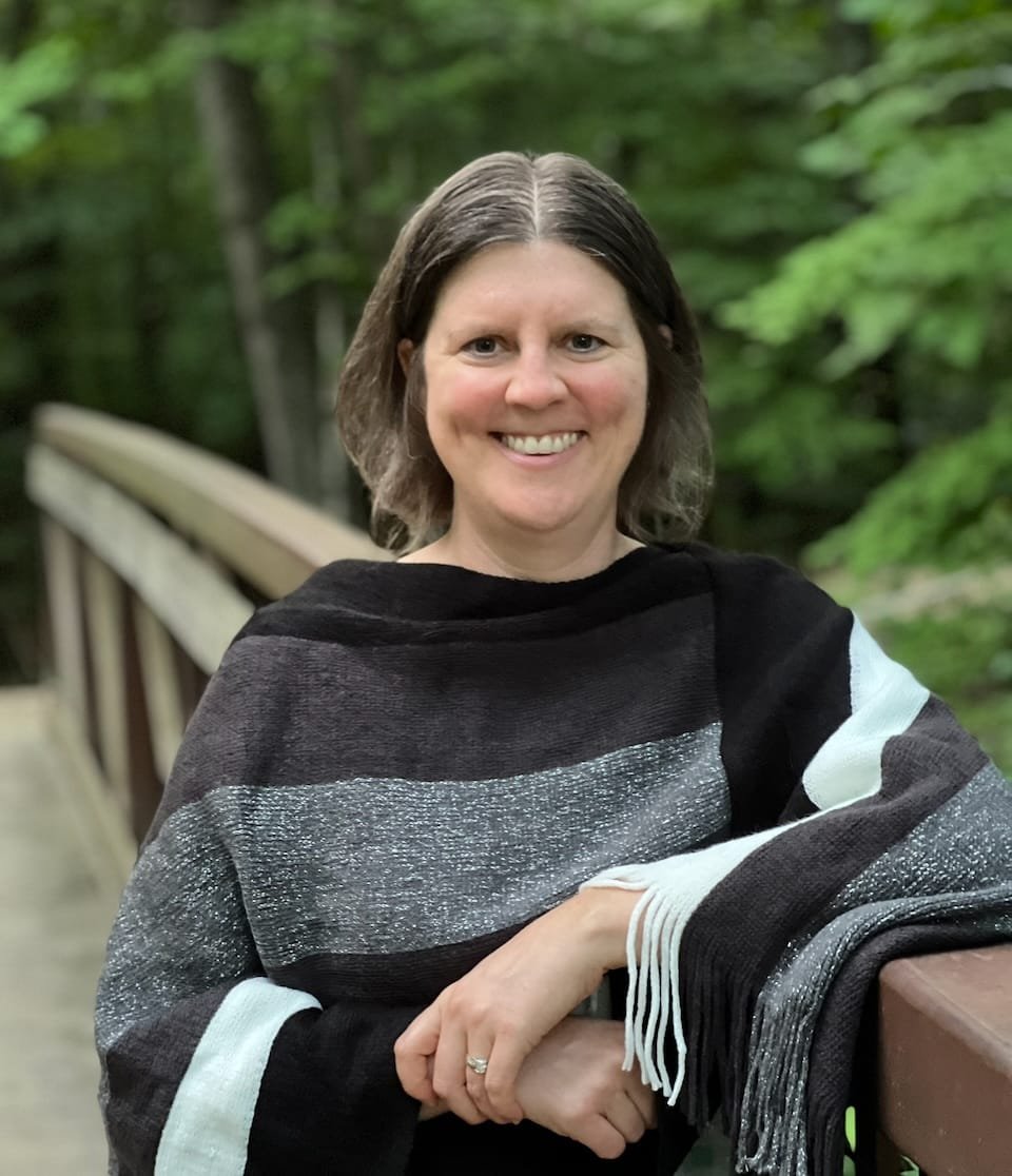 Amy McCrea standing on a wooden footbridge in the woods
